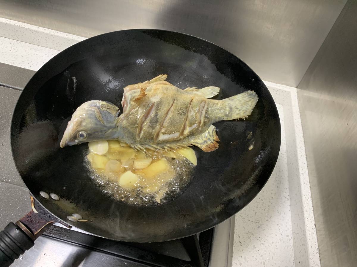将鱼两面煎到黄，加入姜蒜。